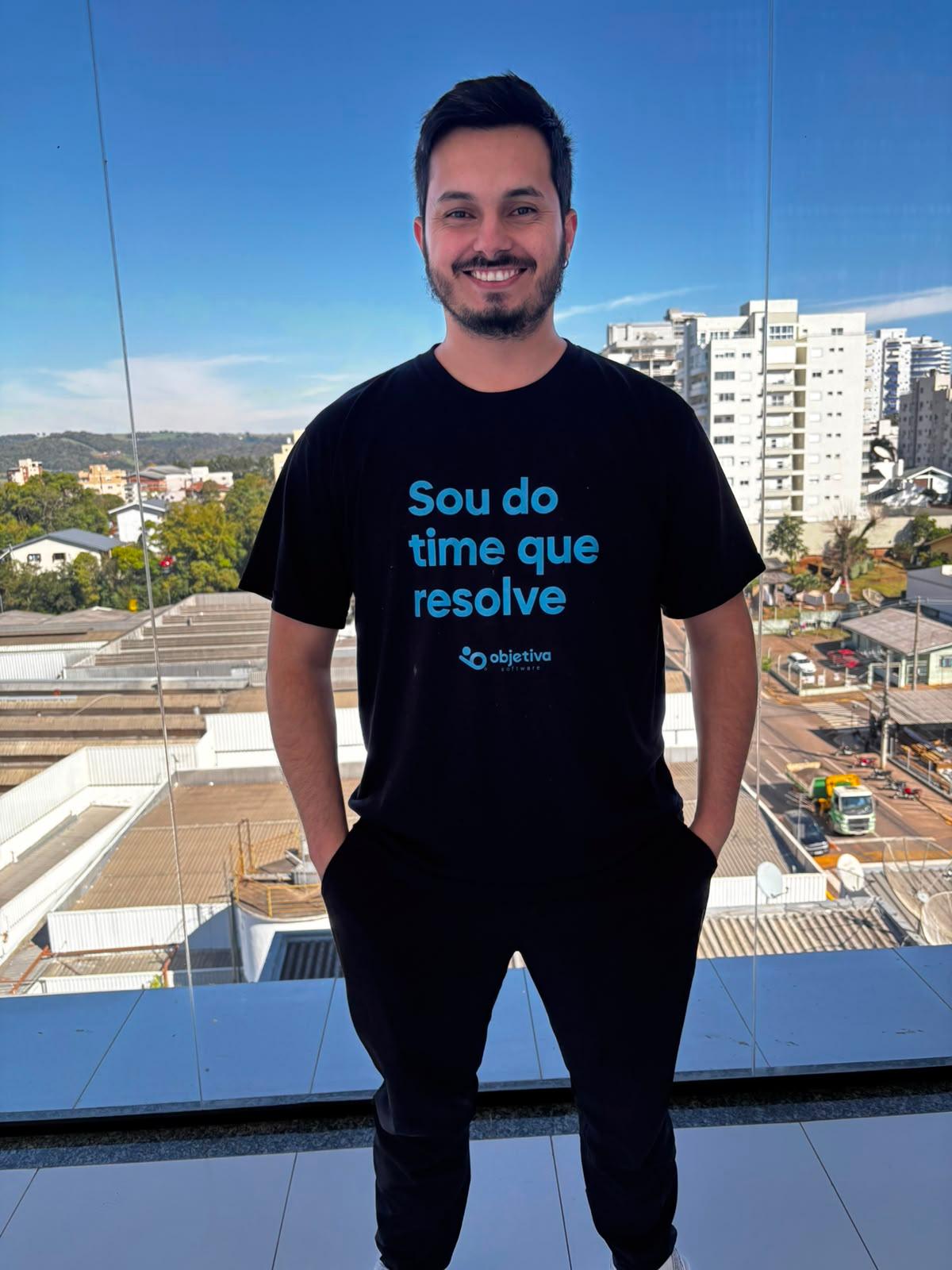 Matheus Maydana de corpo inteiro, sorrindo, na mesma varanda.
